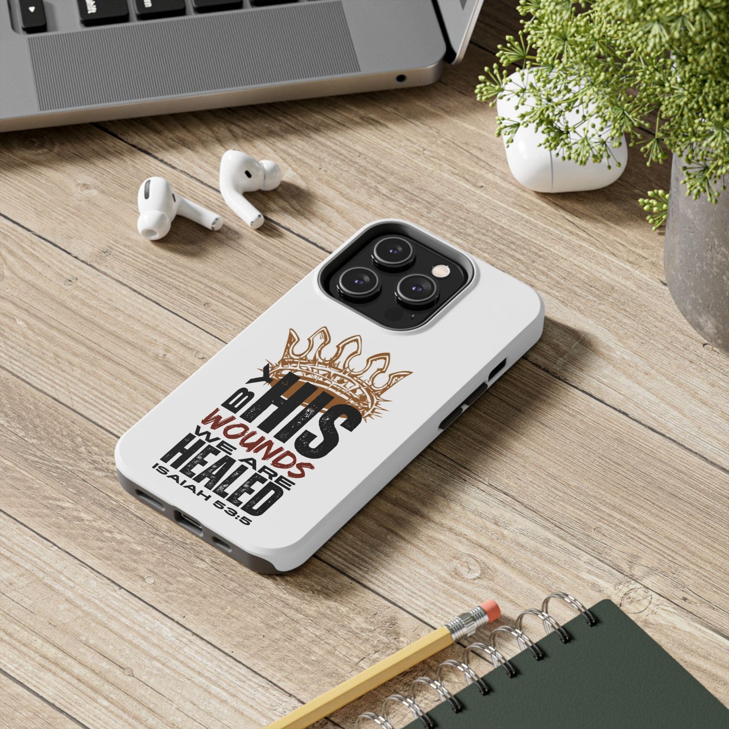 Logos Co. Christian tough phone case with IHS crown design and healing scripture on wood desk