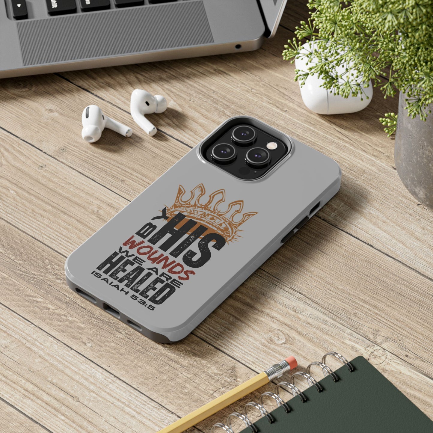 Logos gray scripture phone cover with Isaiah 53:5 Bible verse design featuring a crown on wooden desk