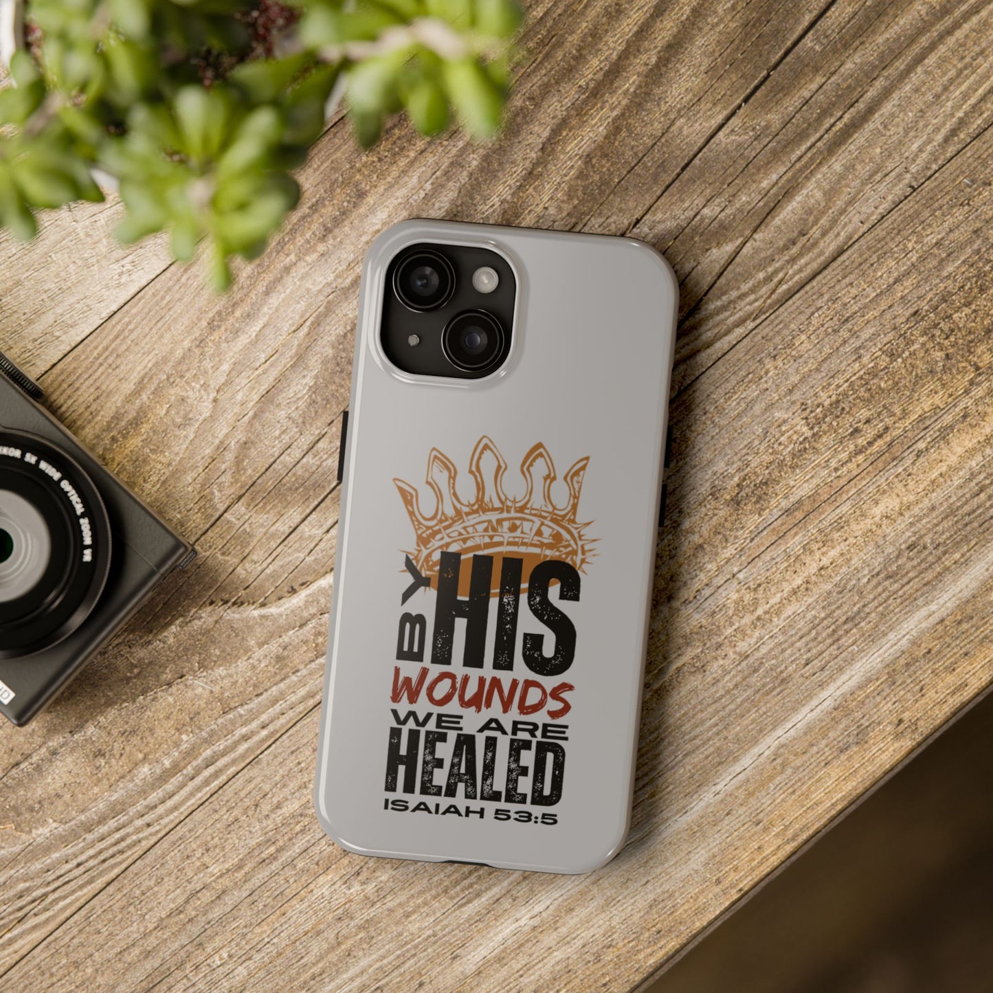 Logos Co. gray scripture phone cover with Isaiah 53:5 healing design on wooden surface