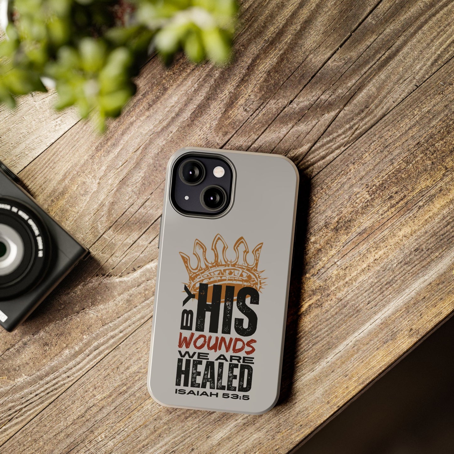 Logos Co. gray scripture phone cover with Isaiah 53:5 Bible verse design on wooden table