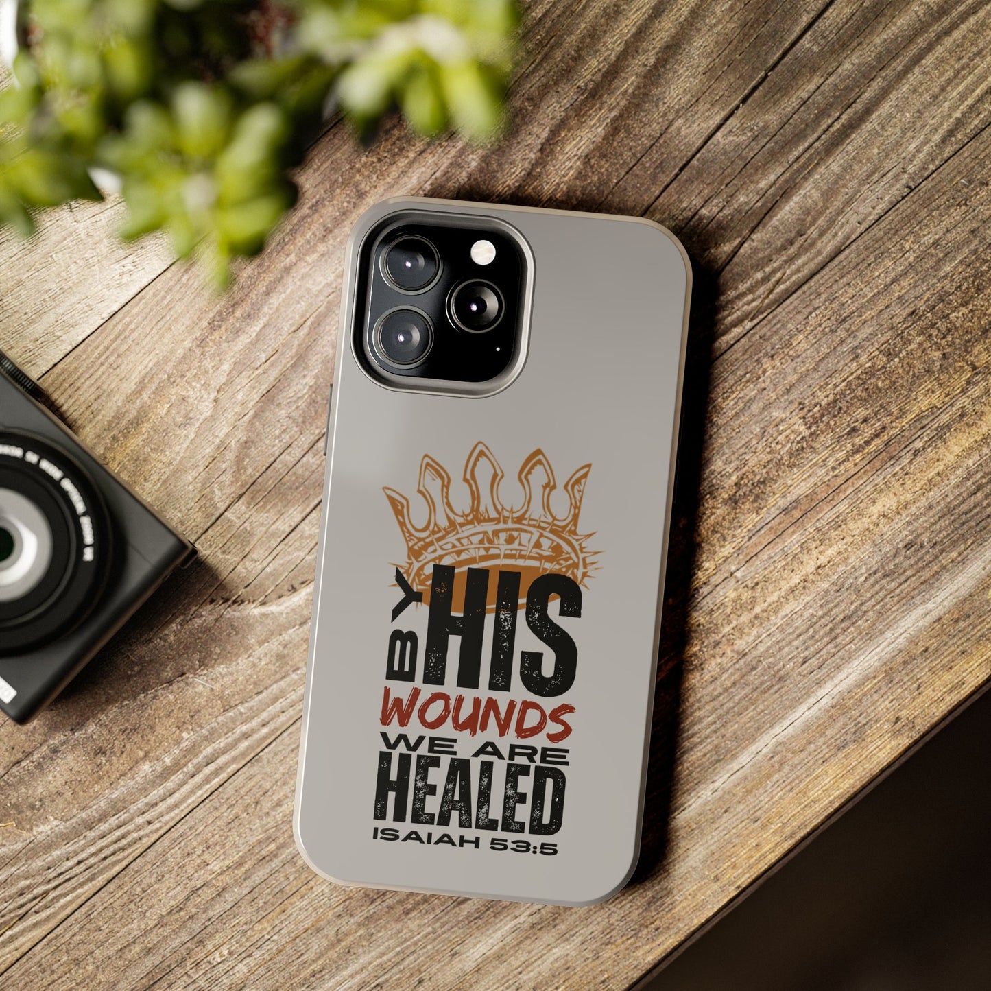 Logos Co. gray scripture phone cover with Isaiah 53:5 design and crown graphic on wooden surface