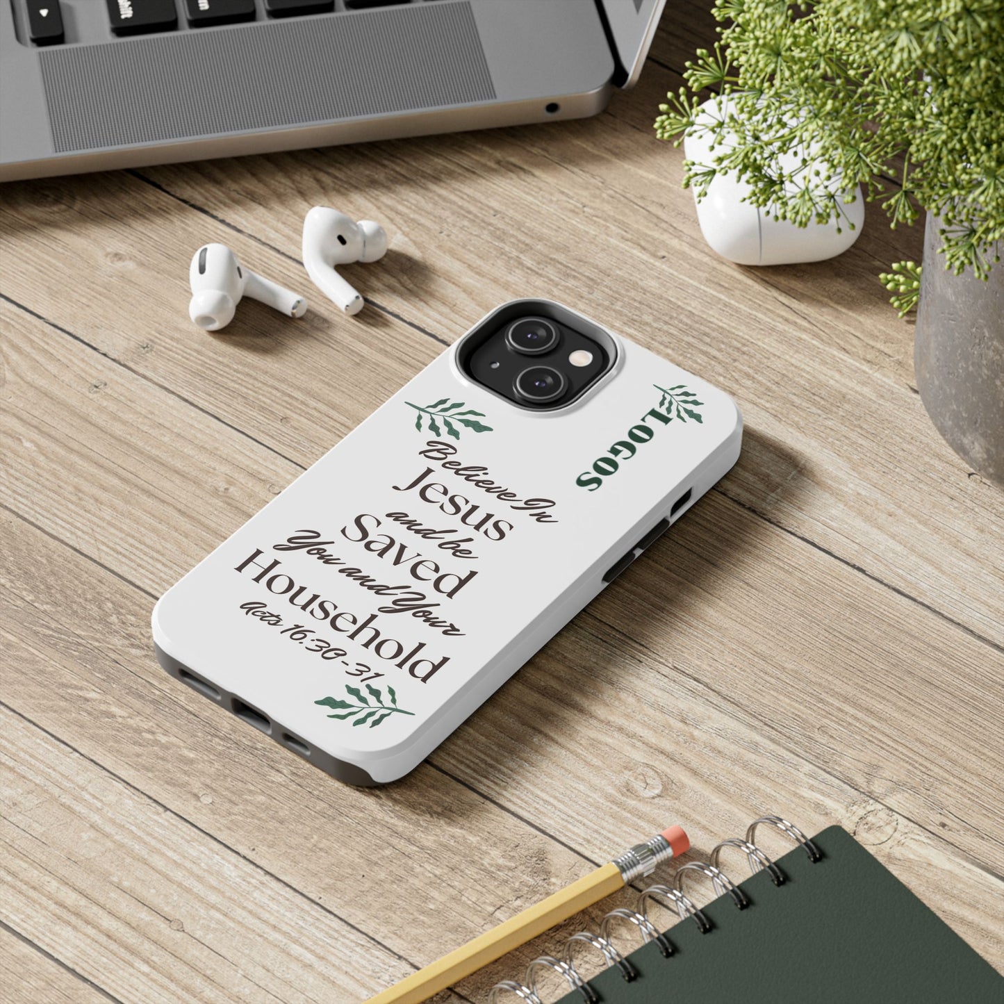 Logos Bible verse phone case with inspirational Christian text and green leaf design placed on wooden desk