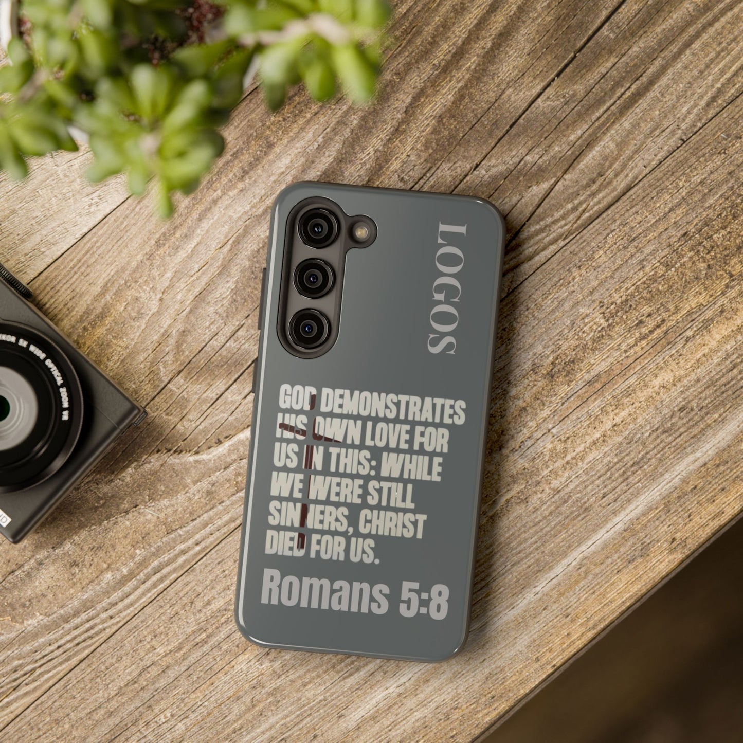 Logos Christian phone case with Romans 5:8 scripture design on gray background