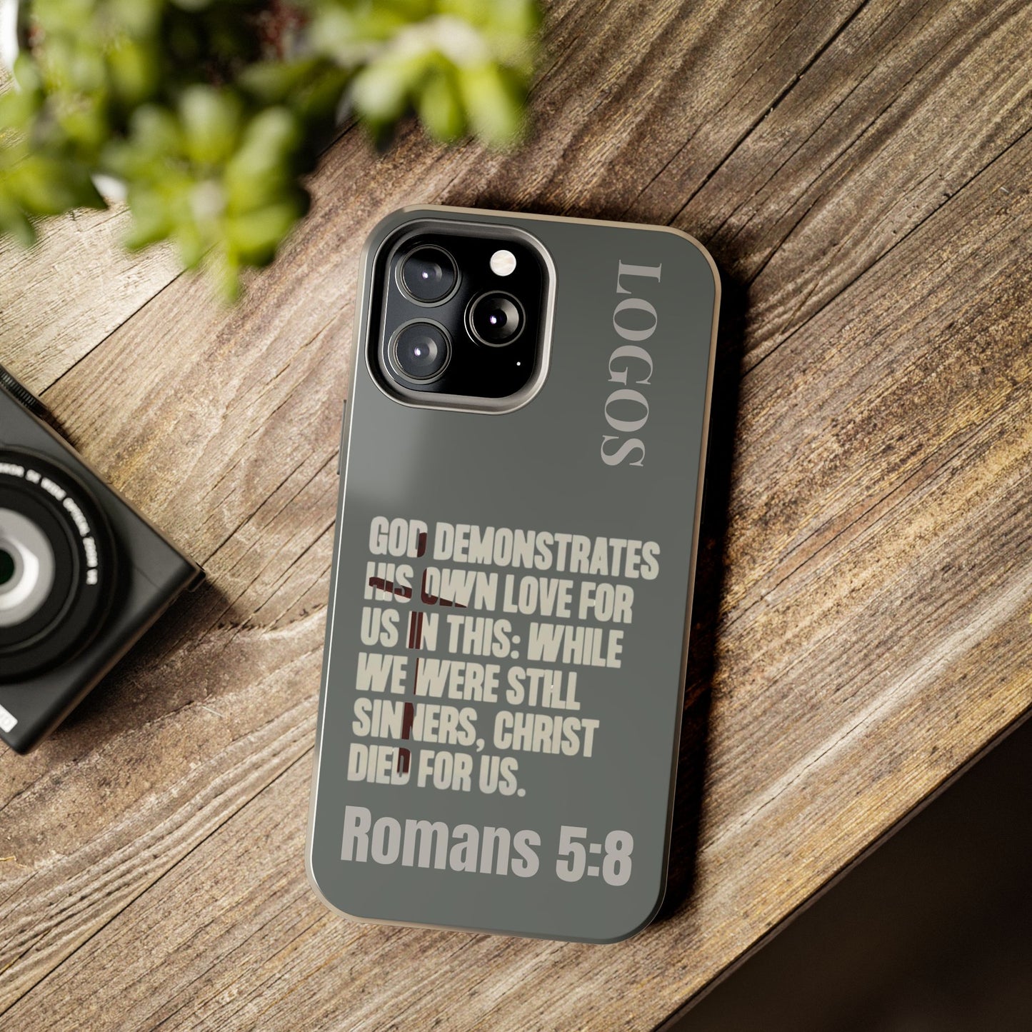 Christian phone case with Romans 5:8 Bible verse quote and LOGOS branding on a dark background