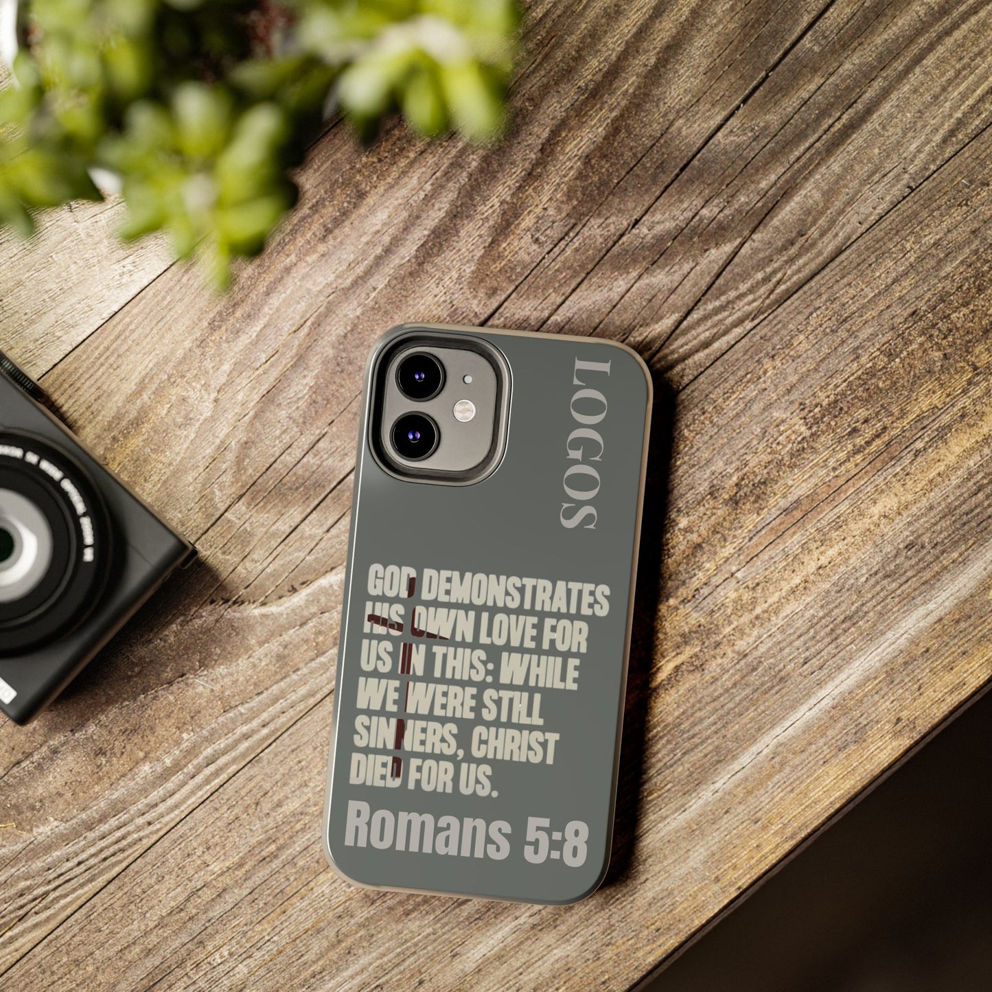 Christian phone case with Romans 5:8 scripture design from Logos on a wooden surface