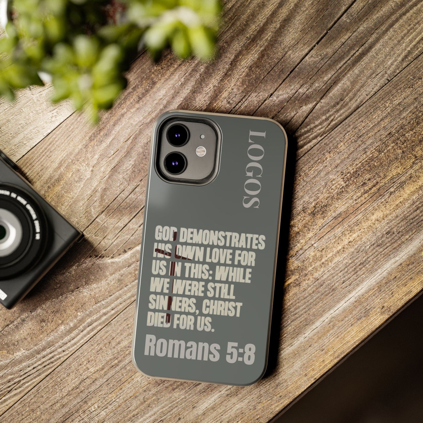 Logos Christian phone case with Romans 5:8 Bible verse quote in gray and beige text