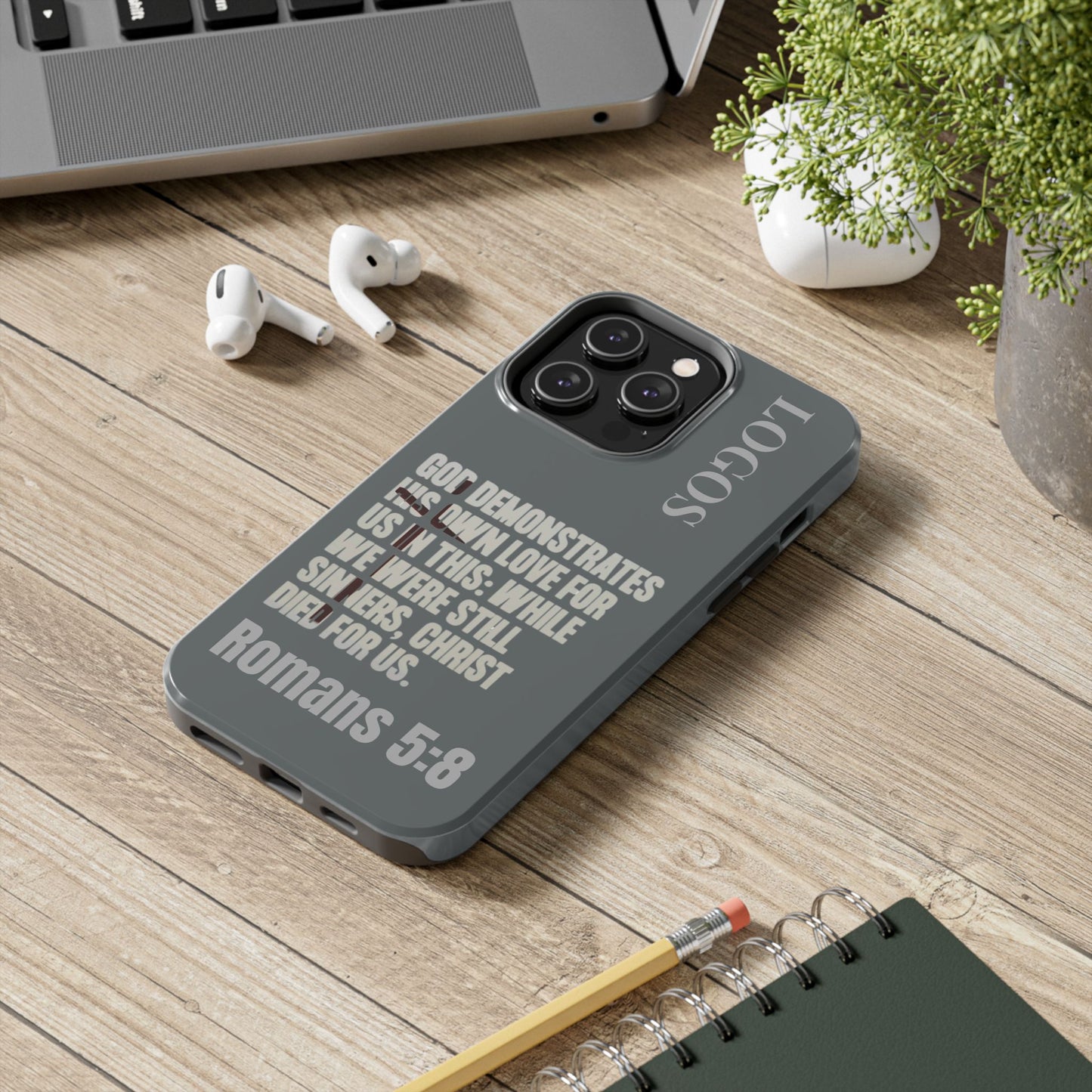 Logos Christian phone case with Bible verse Romans 5:8 on gray protective cover