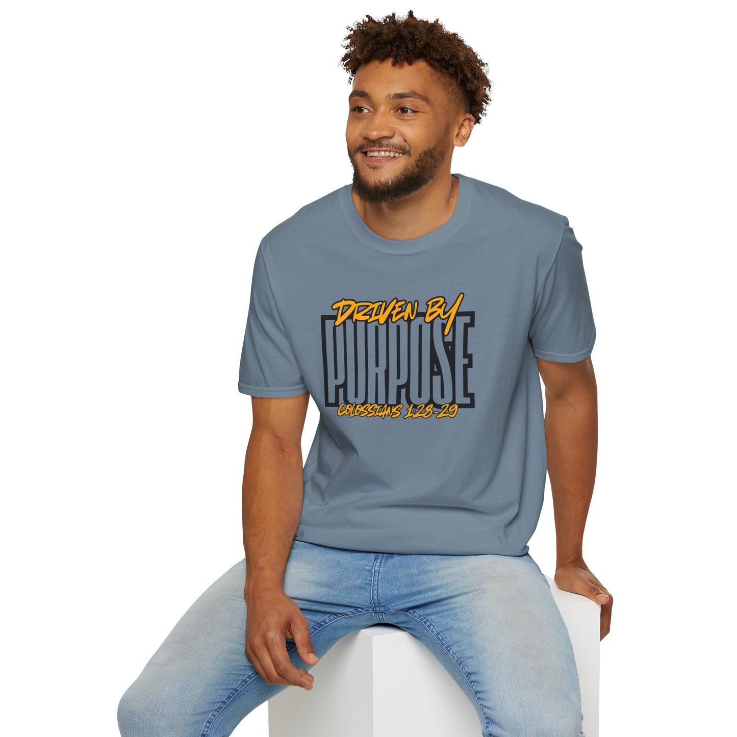 Man wearing blue Driven by Purpose shirt with bold text and casual light jeans sitting on white block