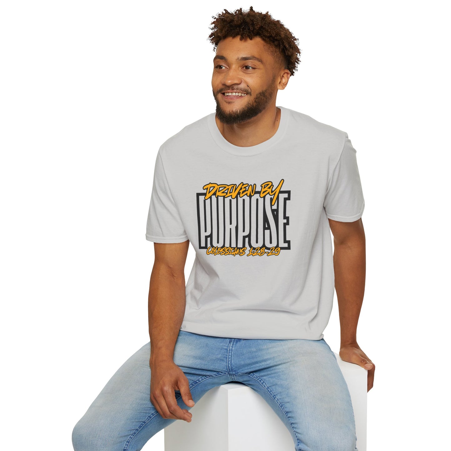 Man wearing a white Driven by Purpose shirt with graphic text and light blue jeans sitting on a white block