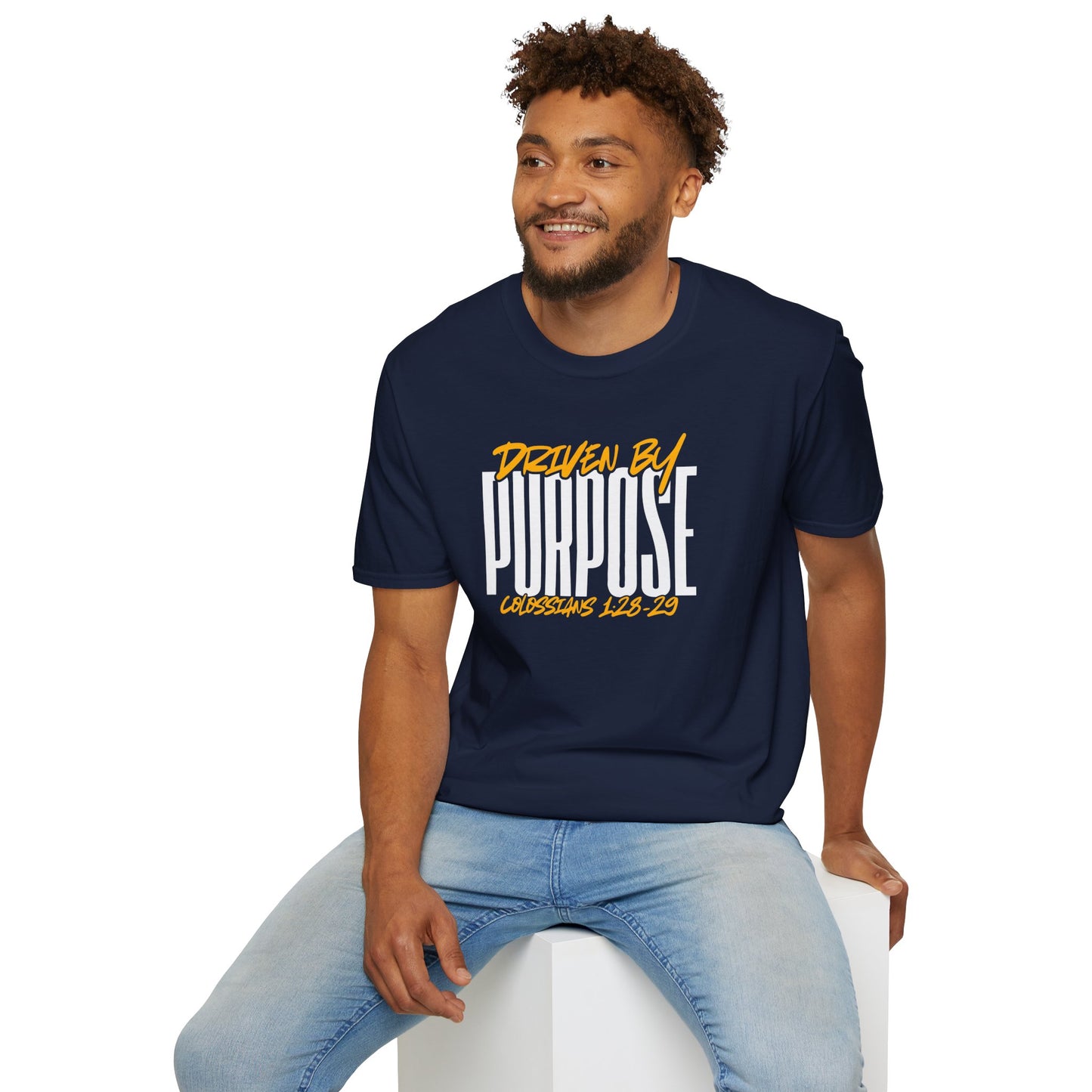 Man wearing navy Driven by Purpose shirt with bold white and yellow text sitting on white block