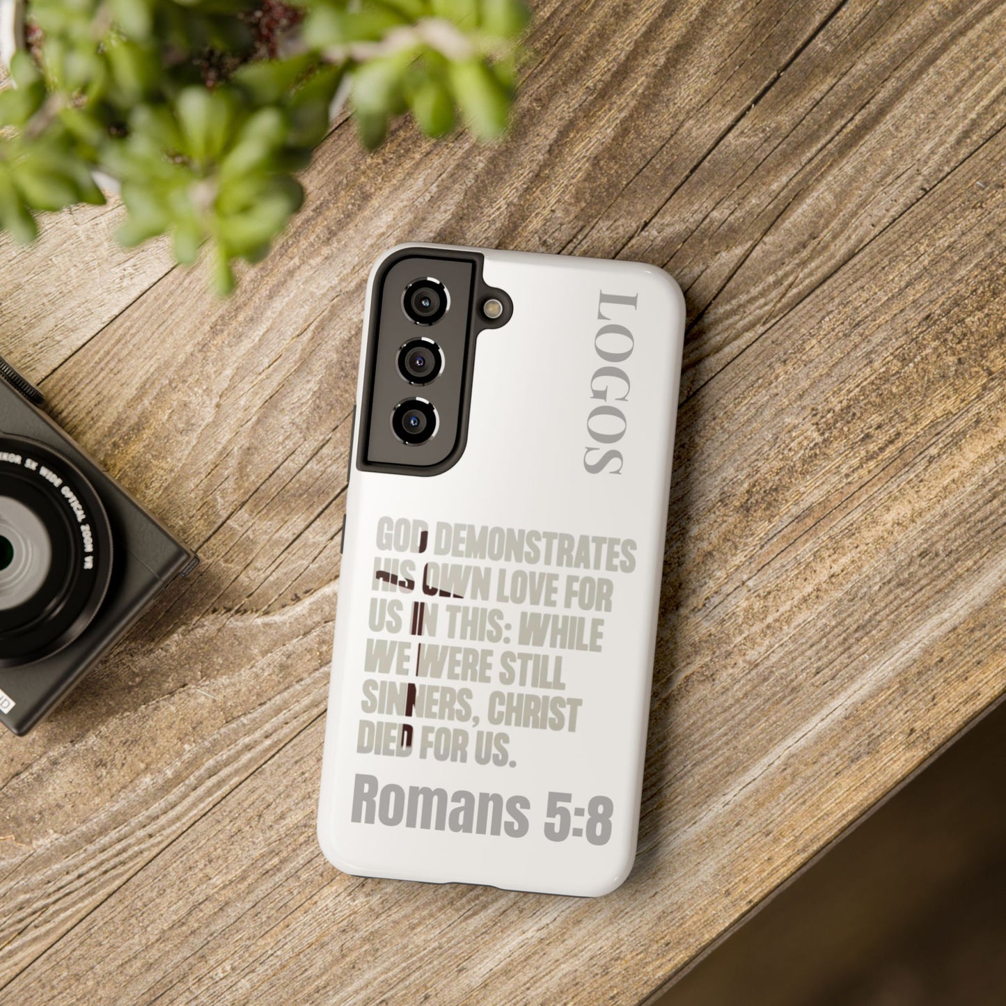Logos Co. faith-based tough cases phone case with Romans 5:8 scripture design on wooden table
