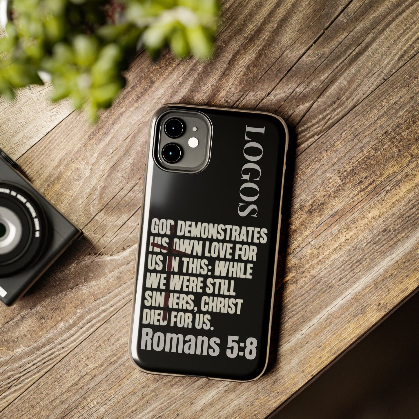 Black Romans 5:8 phone case by Logos featuring inspirational Bible verse design on wooden surface