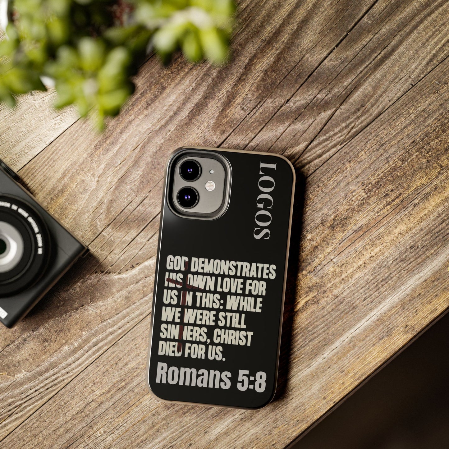 Black Romans 5:8 phone case with inspirational Bible verse design on wooden surface