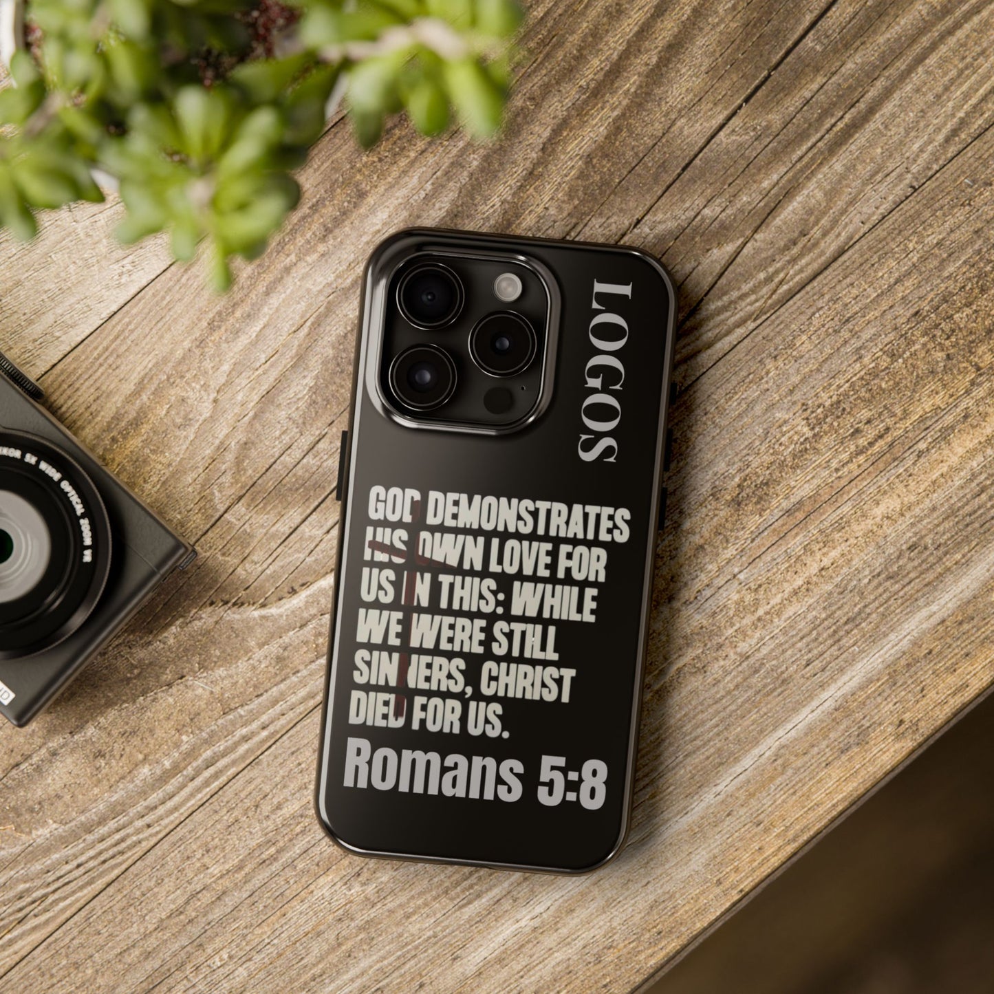 Black Romans 5:8 phone case by Logos with inspirational Bible verse text on wooden surface