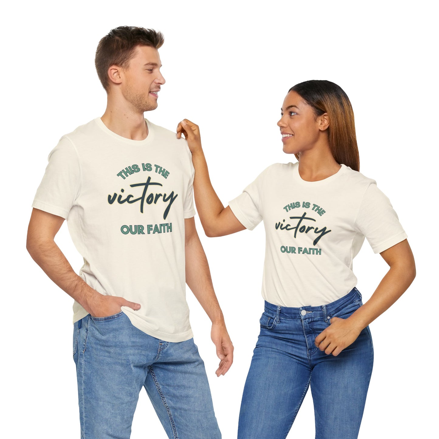 Man and woman wearing This Is The Victory T-shirt in white with faith-themed text design
