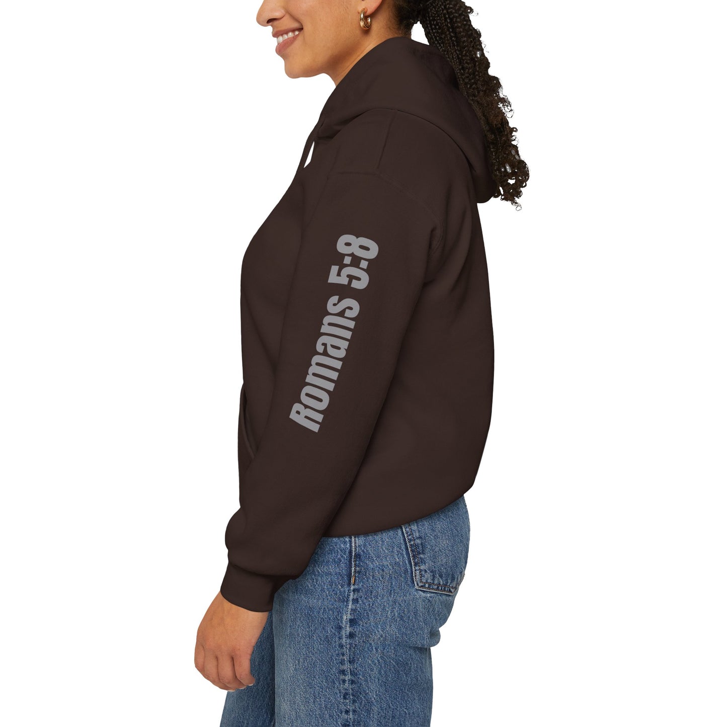 Brown Romans 5:8 hoodie with text printed on sleeve worn by woman in blue jeans