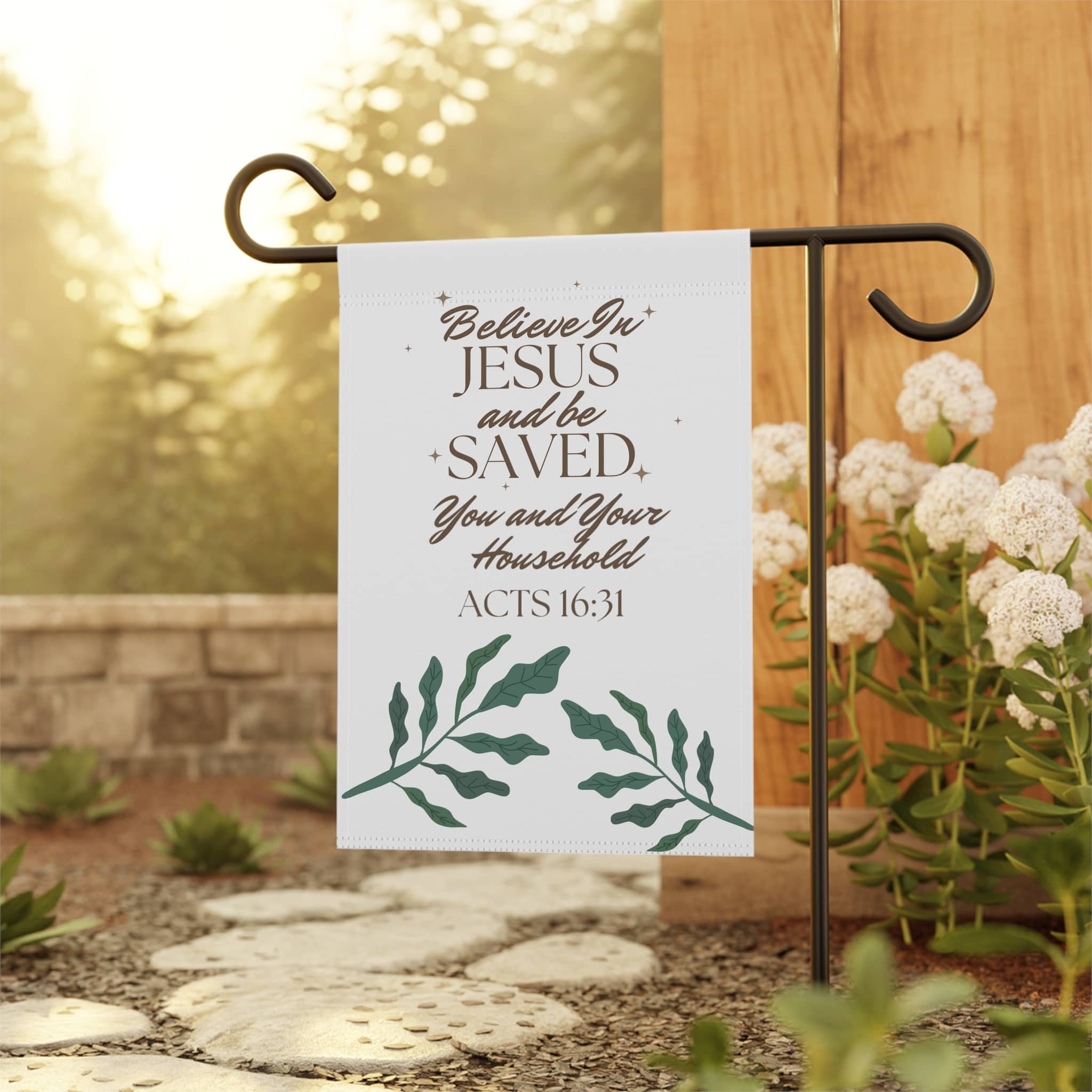 Christian garden banner with scripture quote Acts 16:31 hanging on black metal stand in outdoor garden