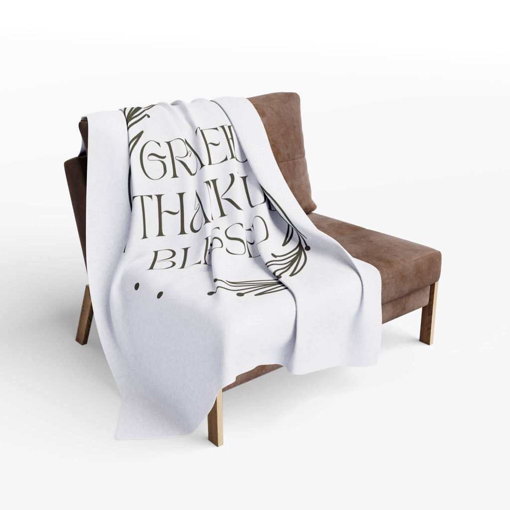 Cozy Christian home decor blanket with a design that says 'Grateful Thankful Blessed' on a chair