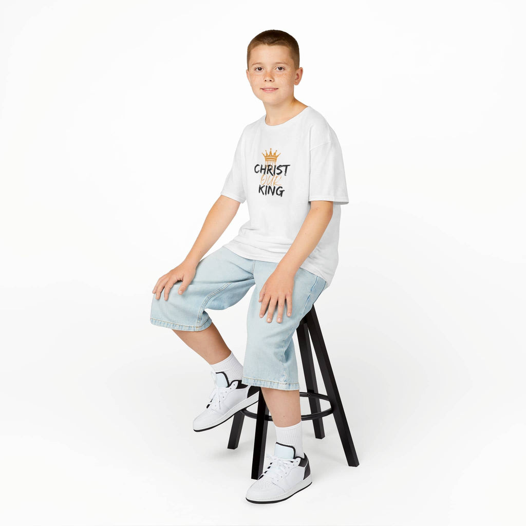 Boy wearing a white Christian junior kids t-shirt with Christ King design sitting on a black stool