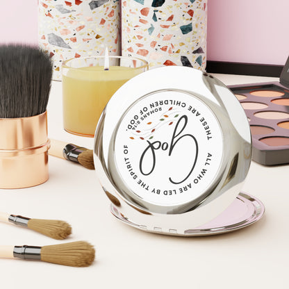 Logos Christian travel mirror with faith-inspired design placed on vanity with makeup brushes and palette