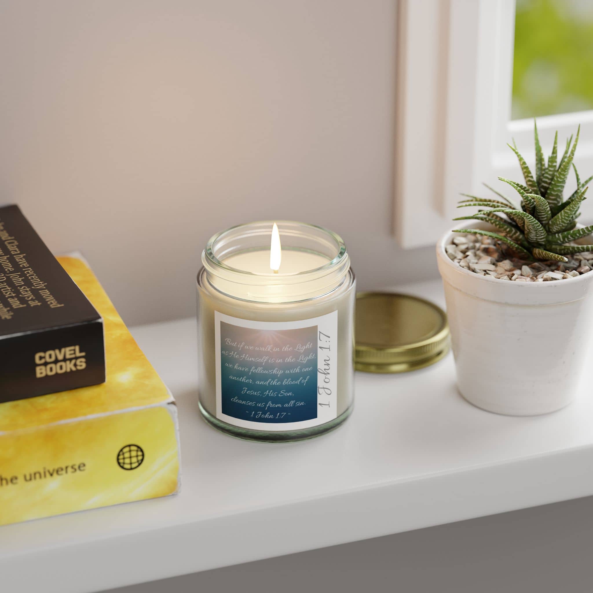 Eco-friendly scripture candle in a glass jar on a shelf next to books and a small potted plant