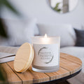 Scented candle with 'Grateful, Thankful, Blessed' phrase, frosted glass holder, and wooden lid on a table