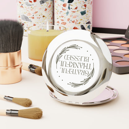 Grateful Thankful Blessed compact mirror on a vanity with makeup brushes and candles