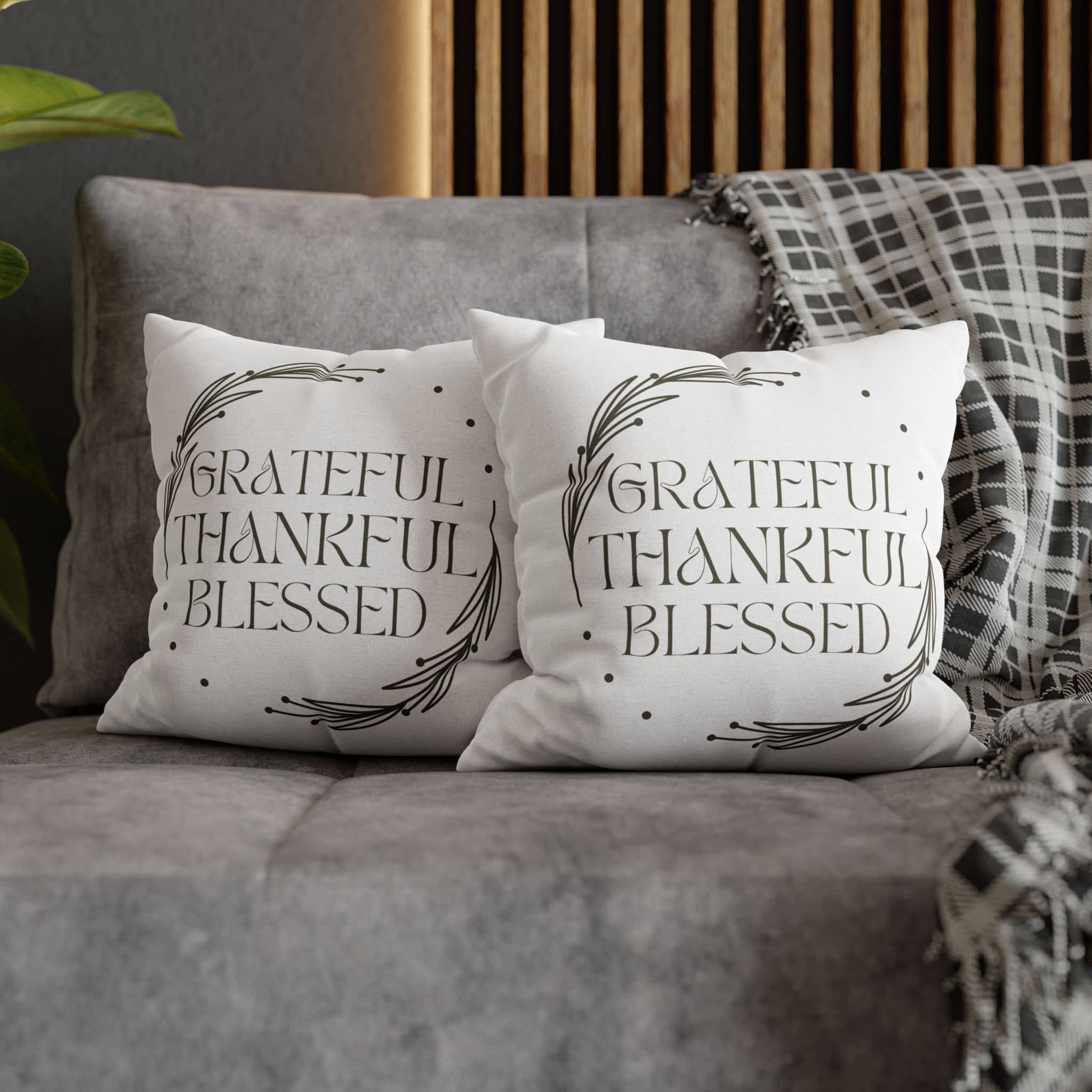 Two decorative pillows on a gray sofa featuring the Grateful Thankful Blessed pillowcase in an elegant design