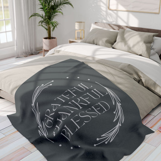 Cozy Grateful Thankful Blessed throw blanket on a light-colored bed in a bright room