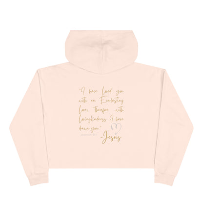Back view of a light pink Jesus Loves Me crop hoodie with a gold inspirational Bible quote and heart design