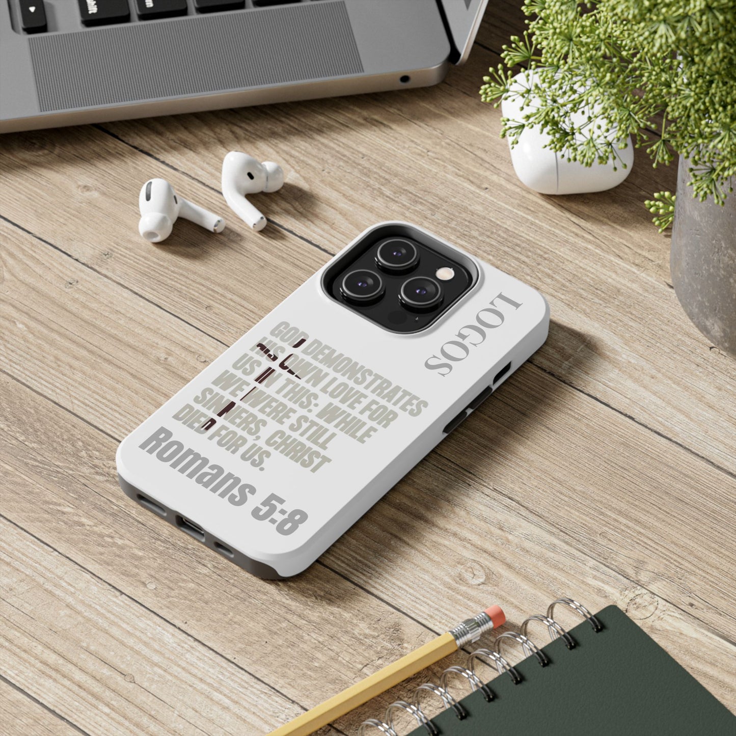 Logos Co. faith-based tough cases phone case with Romans 5:8 scripture design on wooden desk
