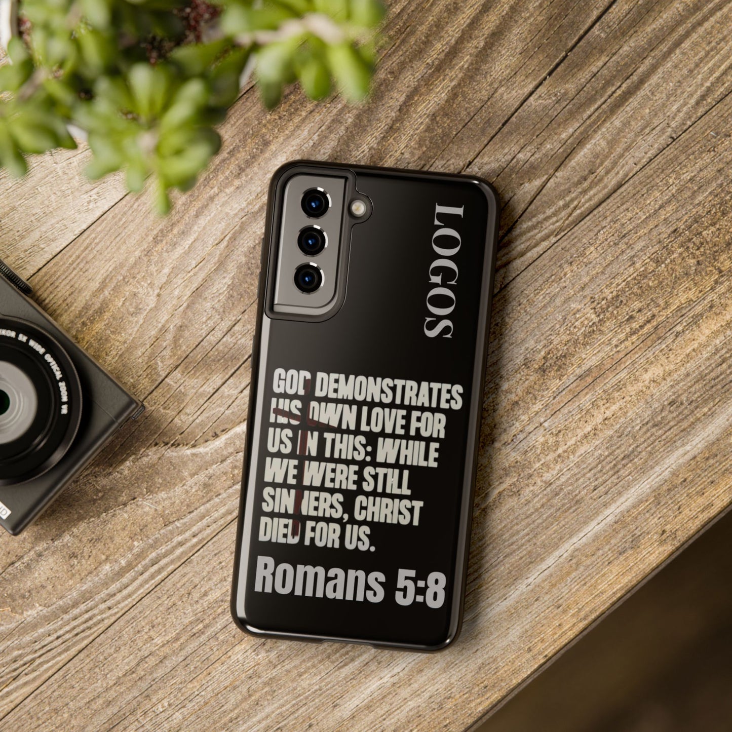 Black Romans 5:8 phone case by Logos with inspirational Bible verse design on wooden surface