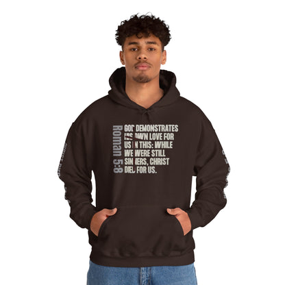 Brown Logos Co. hoodie with Romans 5:8 faith hoodie scripture text design worn by man