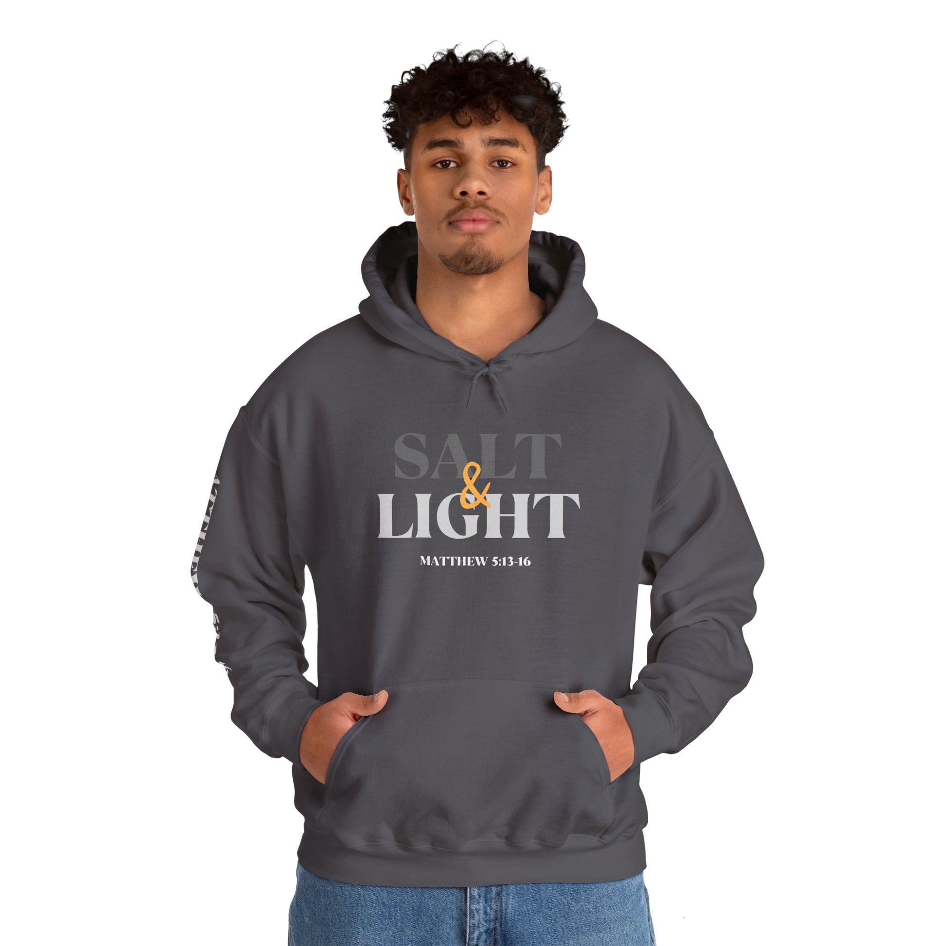 Salt and Light scripture hoodie featuring the front design in charcoal on a man with both hands in the kangaroo pocket