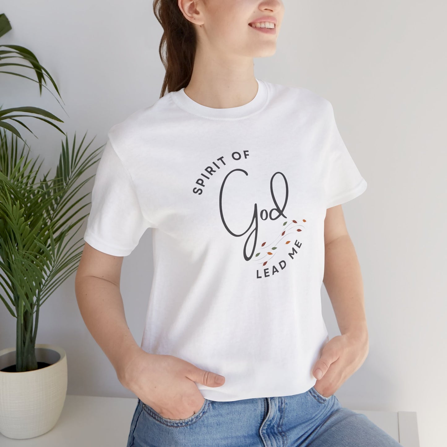 Woman wearing white Spirit Lead Me shirt by Logos with Romans 8:14 themed text design and casual blue jeans