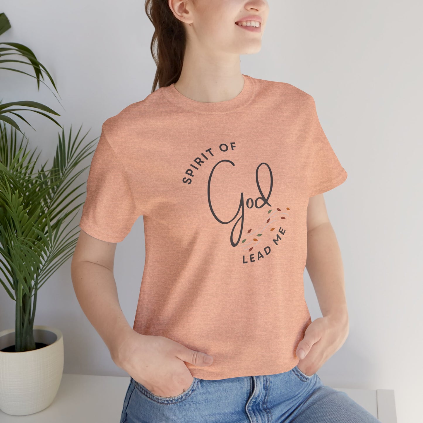 Logos Spirit Lead Me shirt in peach worn by woman with God text design and casual blue jeans