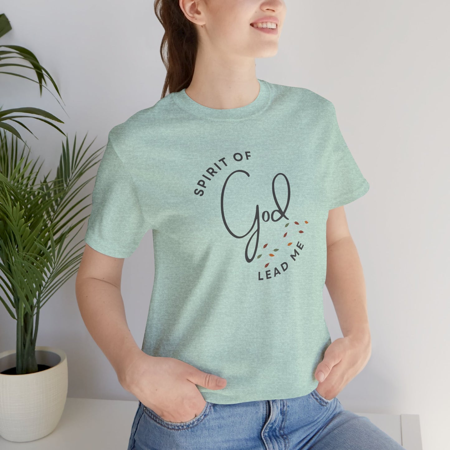 Light green Spirit Lead Me shirt with God text worn by a woman sitting by a plant