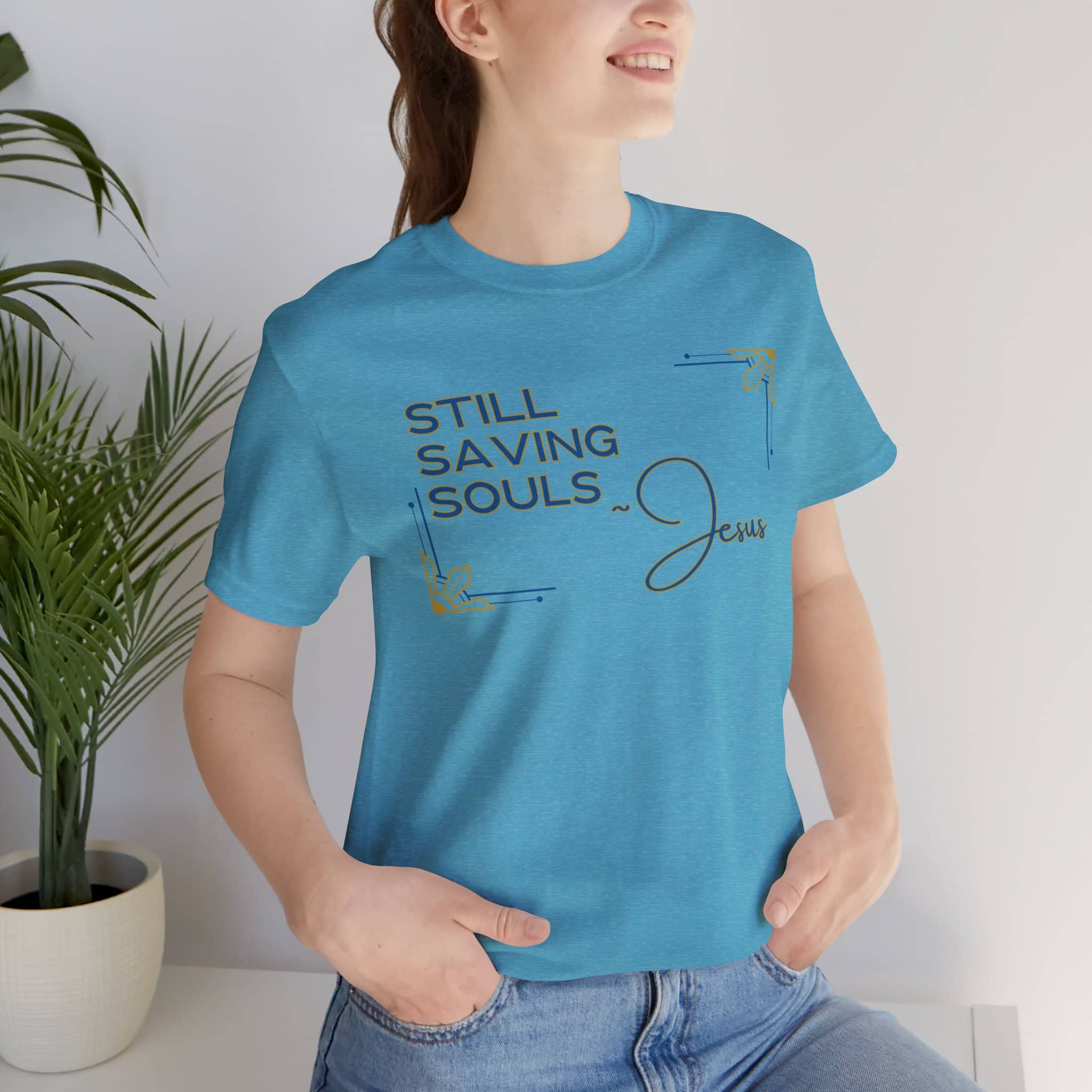 Blue Still Saving Souls shirt worn by smiling woman with hands in pockets