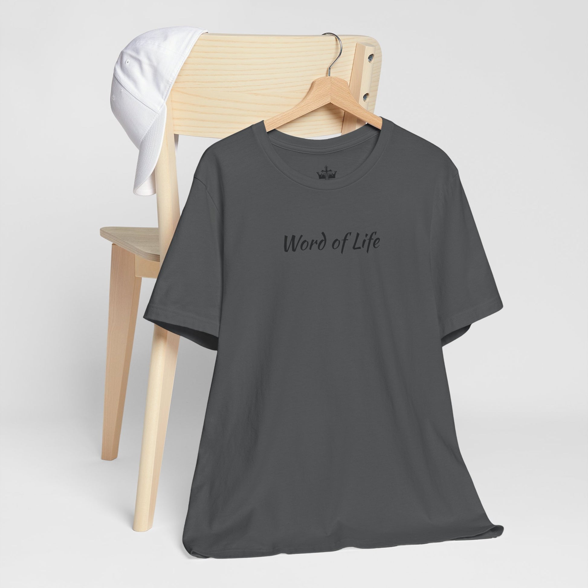 Gray Word of Life Christian shirt hanging on wooden chair with white cap on chair back