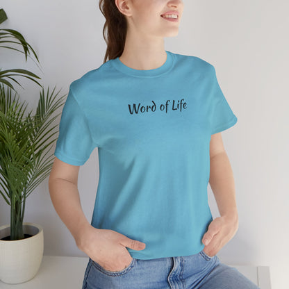 Woman wearing a light blue Word of Life Christian shirt sitting beside a potted plant