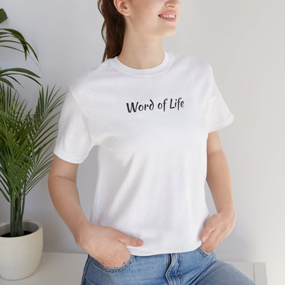 White Word of Life Christian shirt on woman wearing blue jeans standing near a plant